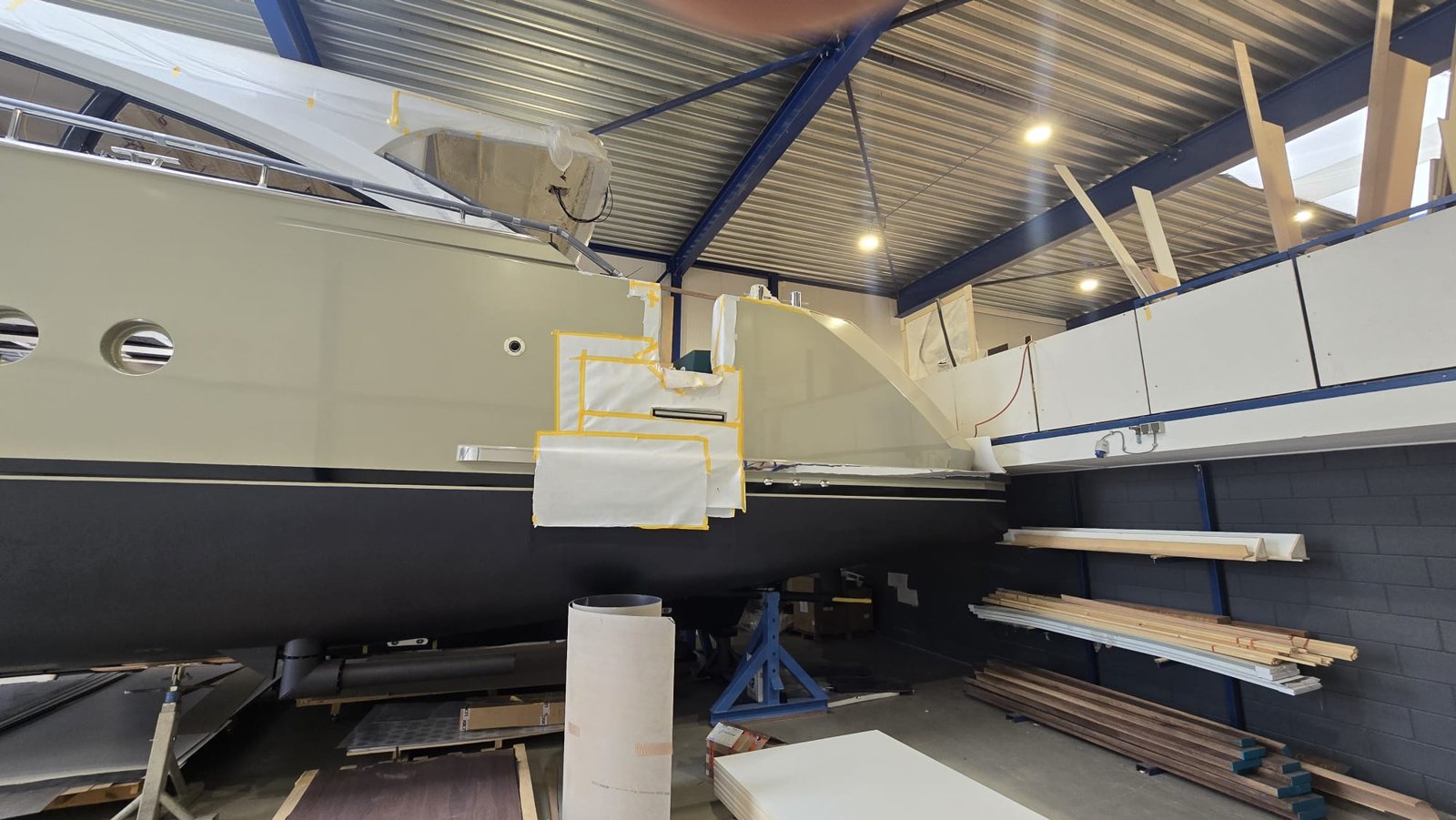 Beige romp met donker onderwaterschip, plaatselijk afgeplakt voor spuitwerk