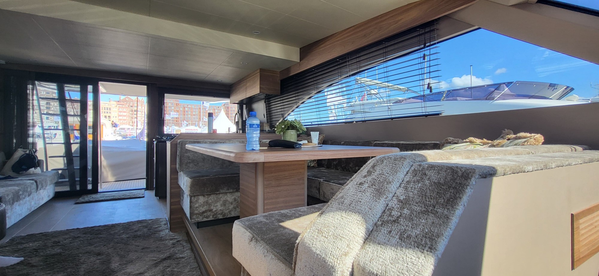 Salon van de VDH SF 65 met zithoek, tafel en openslaand raam naar de kuip